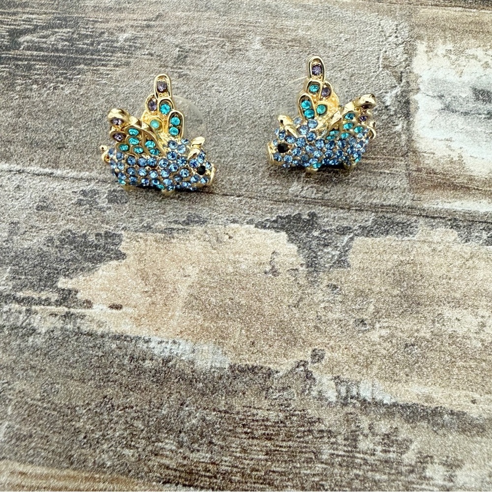 Gold toned and jeweled flying pig novelty earrings.